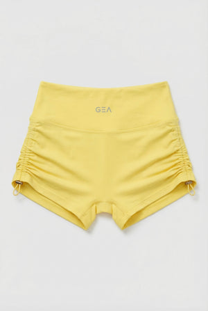 Yellow shorts with a brand logo on a light gray background