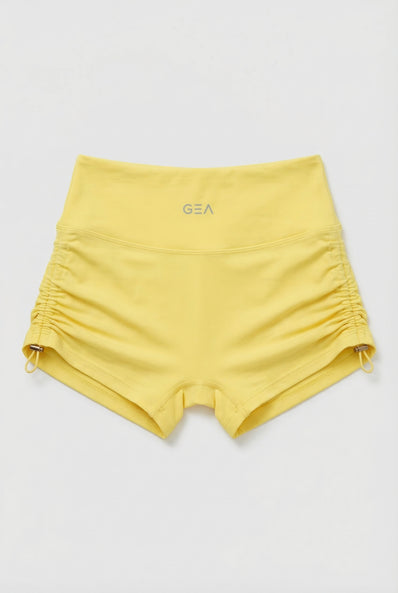 Yellow shorts with a brand logo on a light gray background