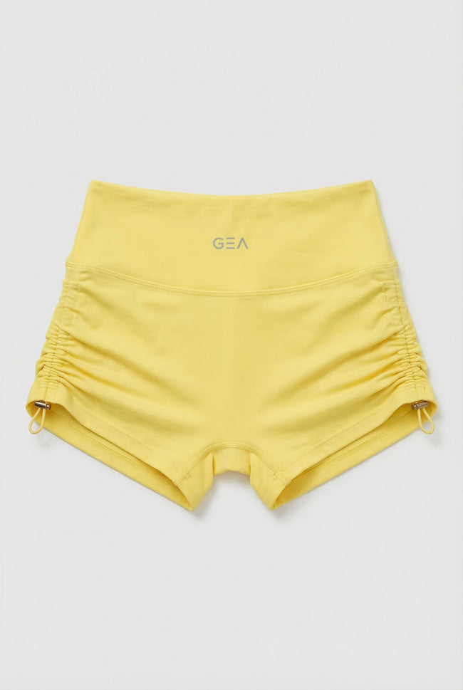 Yellow shorts with a brand logo on a light gray background