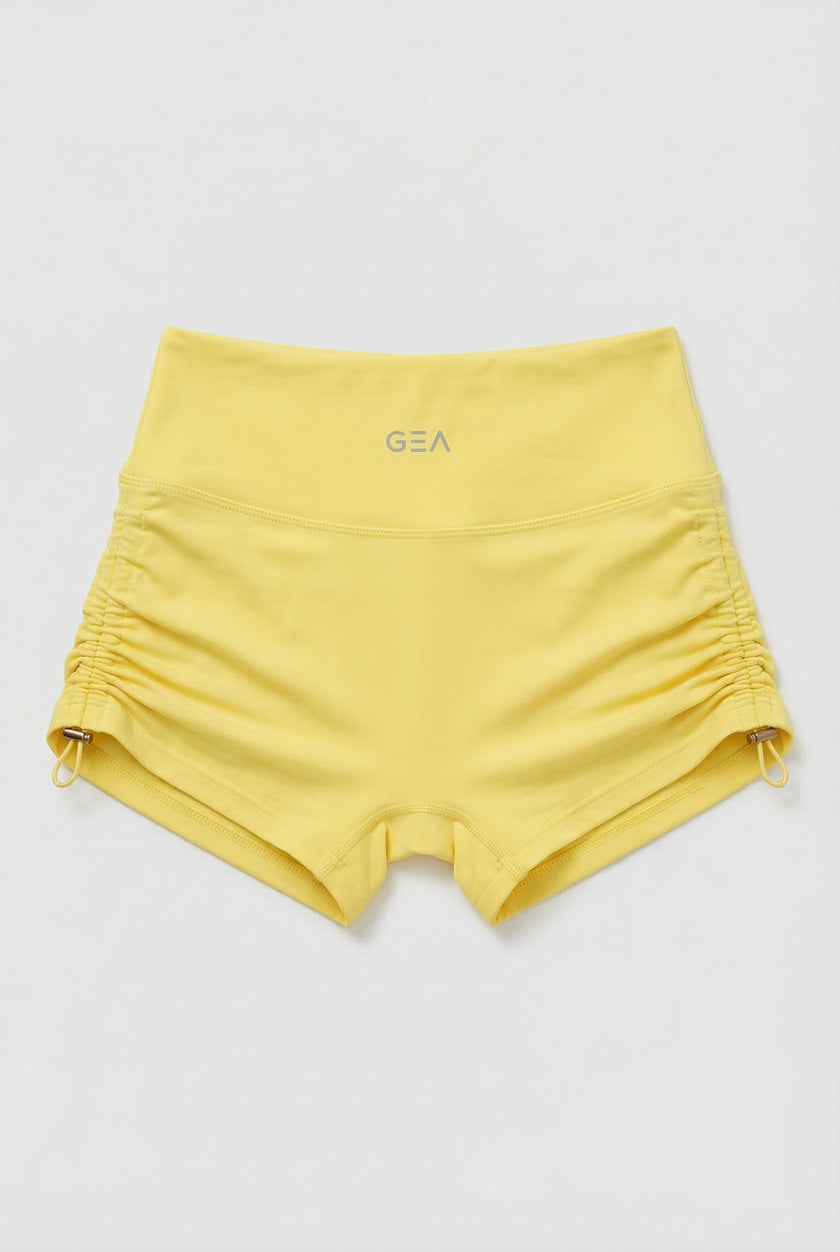 Yellow shorts with a brand logo on a light gray background